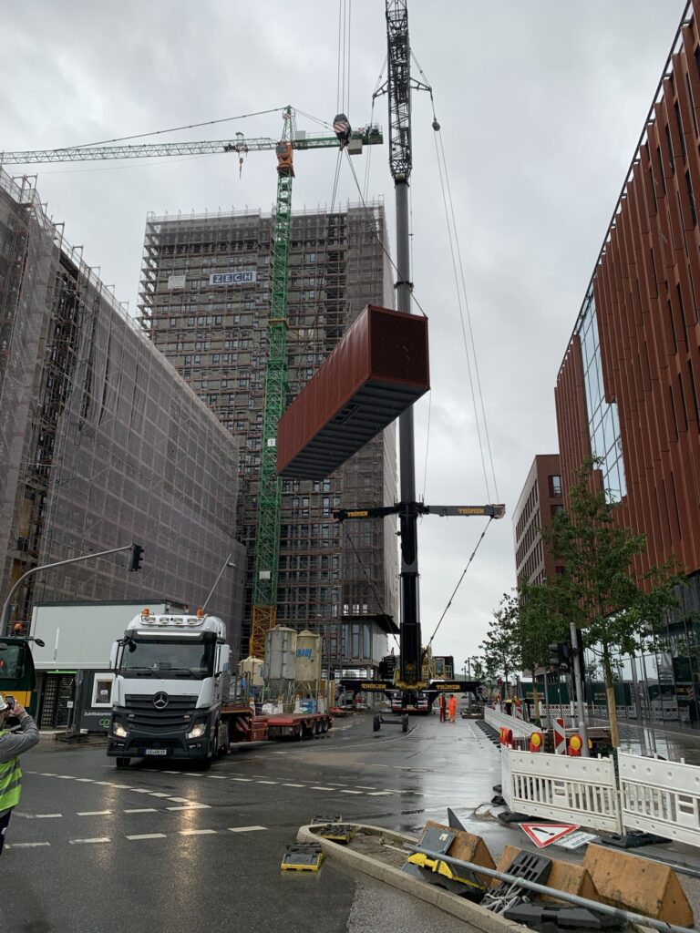 Anlagencontainer wird per Mobilkran auf die Baustelle gehoben
